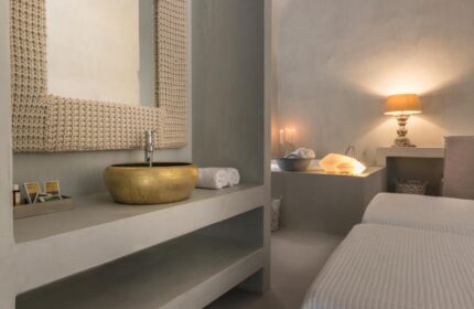 Bathroom at Mythical Blue Luxury Suites, a gay-friendly hotel. Gold sink, woven mirror frame, and soft lighting create a relaxing ambiance.