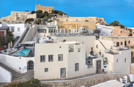 Mythical Blue Luxury Suites, a gay-friendly hotel. Whitewashed buildings with pool, rooftop dining, and castle in Santorini, Greece.