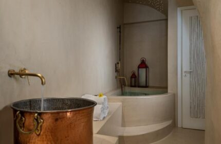Mythical Blue Luxury Suites gay-friendly hotel bathroom. Copper sink, jacuzzi tub, and ambient lighting for gay travel relaxation.