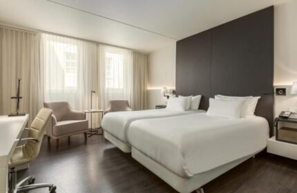 NH Collection Amsterdam Barbizon Palace gay-friendly hotel room. Two beds, desk, and chairs. Modern design, comfortable for gay travelers.