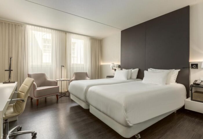 NH Collection Amsterdam Barbizon Palace gay-friendly hotel room. Two beds, desk, and chairs. Modern design, comfortable for gay travelers.