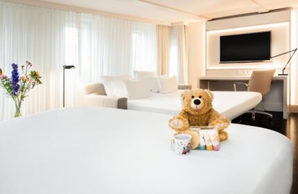 NH Collection Amsterdam Barbizon Palace room with teddy bear, mug, toiletries. Gay-friendly hotel for LGBTQ+ travelers in Amsterdam.