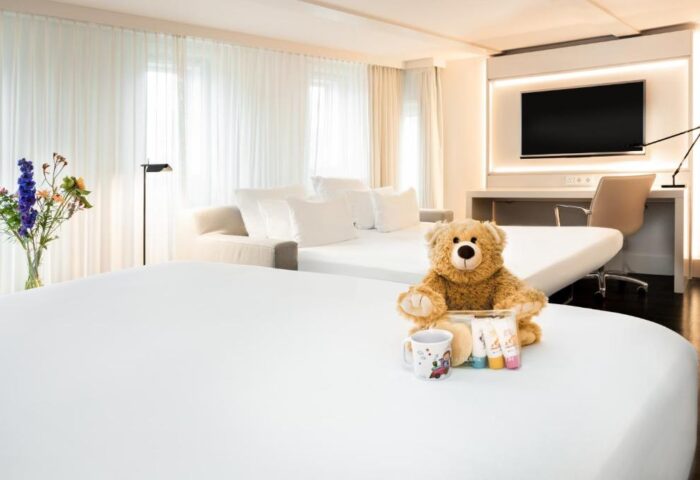 NH Collection Amsterdam Barbizon Palace room with teddy bear, mug, toiletries. Gay-friendly hotel for LGBTQ+ travelers in Amsterdam.