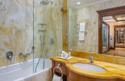 Bathroom at NH Collection Carlo IV, a gay-friendly, pet-friendly hotel. Features a bathtub, shower, marble walls, and a glimpse into the room.