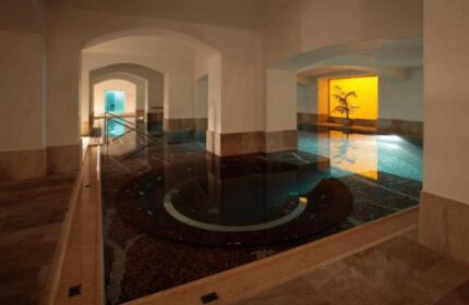 Indoor pool at NH Collection Carlo IV, a gay-friendly, pet-friendly hotel. Arched doorways, marble floors, and a relaxing atmosphere.