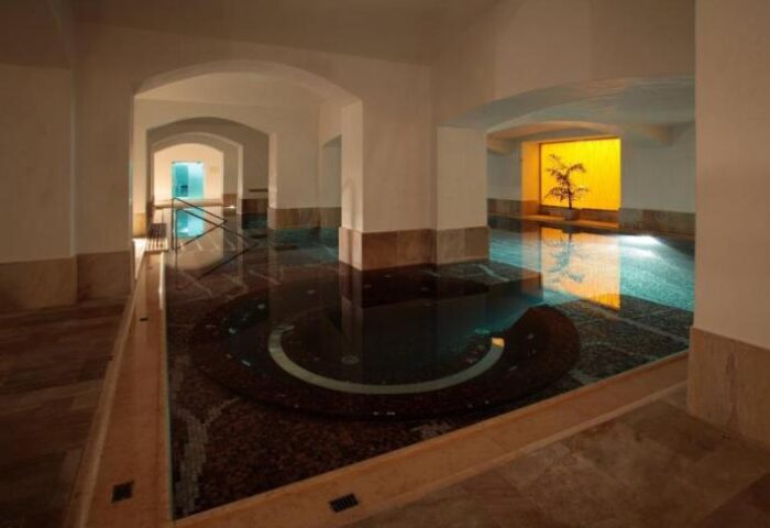 Indoor pool at NH Collection Carlo IV, a gay-friendly, pet-friendly hotel. Arched doorways, marble floors, and a relaxing atmosphere.