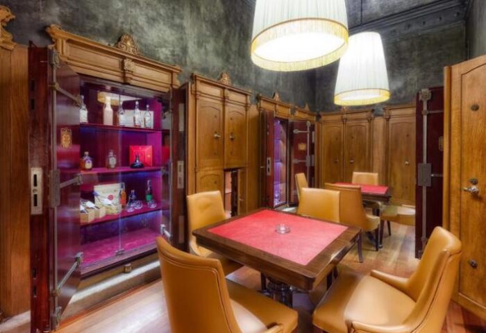 NH Collection Carlo IV gay-friendly hotel's unique bar area. Vault-like cabinets display liquor. Tables and chairs create an intimate setting.