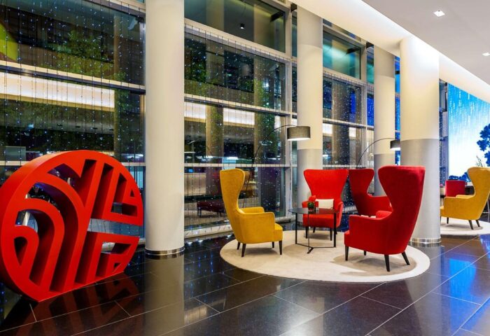 Lobby at the gay-friendly NH Collection Frankfurt City hotel. Red and yellow chairs, modern design, and a welcoming atmosphere for gay travelers.