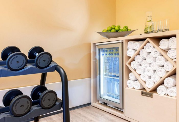 NH Collection Frankfurt City gym. Dumbbells, water bottles, and rolled towels. Gay-friendly hotel fitness center amenities.