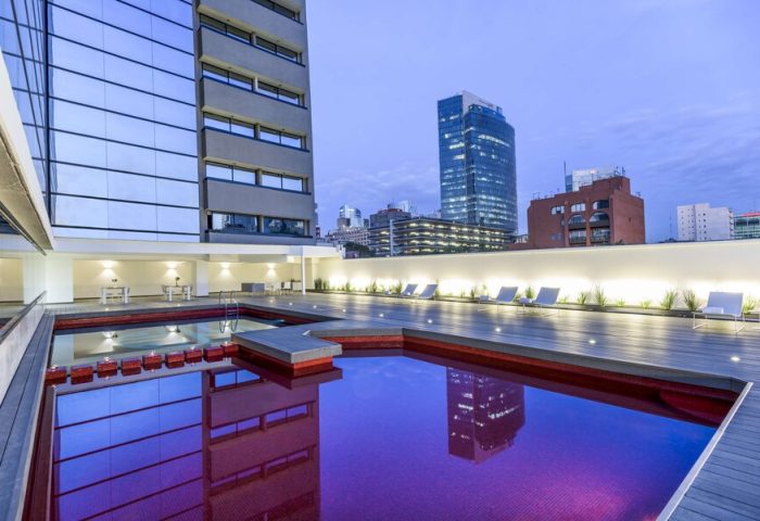 Rooftop pool at NH Collection Mexico City Reforma, a gay-friendly hotel. Loungers line the deck with city views. Building reflects in the water.