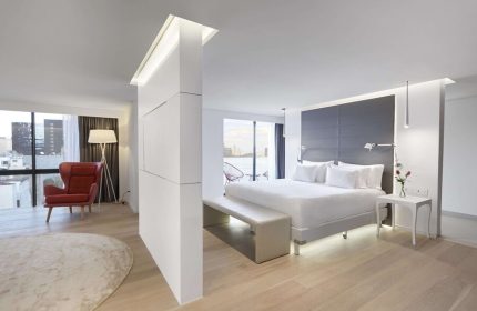 NH Collection Mexico City Reforma gay-friendly hotel room. Modern design with a king bed, red chair, and city view. Ideal for gay travelers.