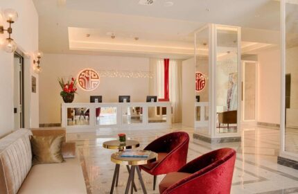 Lobby at NH Collection Palazzo Cinquecento, a gay-friendly hotel. Reception area with red chairs, desk, and modern design elements.