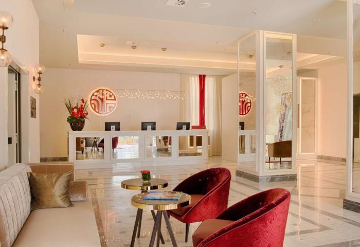 Lobby at NH Collection Palazzo Cinquecento, a gay-friendly hotel. Reception area with red chairs, desk, and modern design elements.