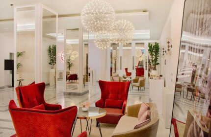 NH Collection Palazzo Cinquecento's gay-friendly hotel lobby. Modern design with red chairs, sofas, and spherical chandeliers.