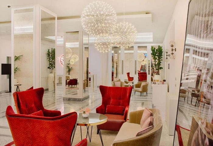 NH Collection Palazzo Cinquecento's gay-friendly hotel lobby. Modern design with red chairs, sofas, and spherical chandeliers.