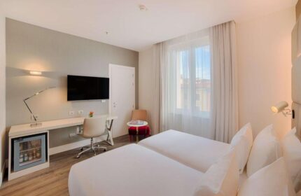 NH Collection Palazzo Cinquecento gay-friendly hotel room. Twin beds, desk, TV, and mini-fridge. Modern design, comfortable for gay travelers.
