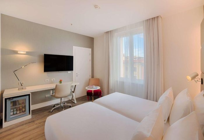 NH Collection Palazzo Cinquecento gay-friendly hotel room. Twin beds, desk, TV, and mini-fridge. Modern design, comfortable for gay travelers.