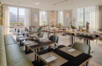 NH Milano Palazzo Moscova gay-friendly hotel restaurant. Tables set for breakfast. Buffet with fruit & pastries. Bright, airy space.