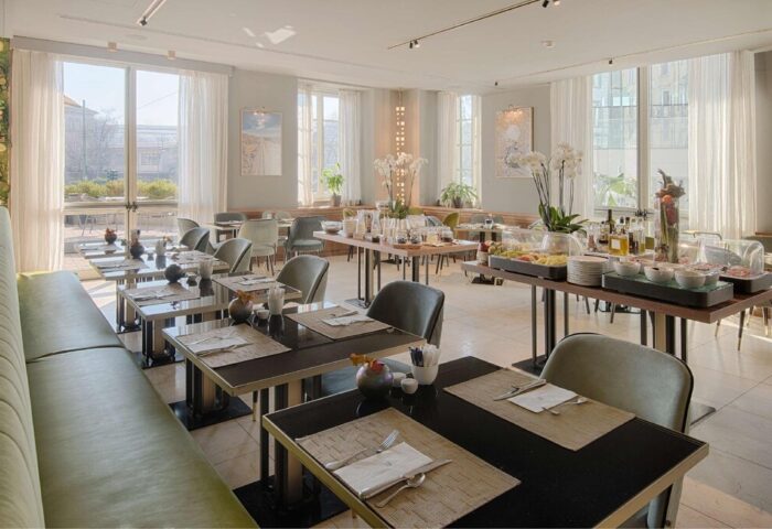 NH Milano Palazzo Moscova gay-friendly hotel restaurant. Tables set for breakfast. Buffet with fruit & pastries. Bright, airy space.