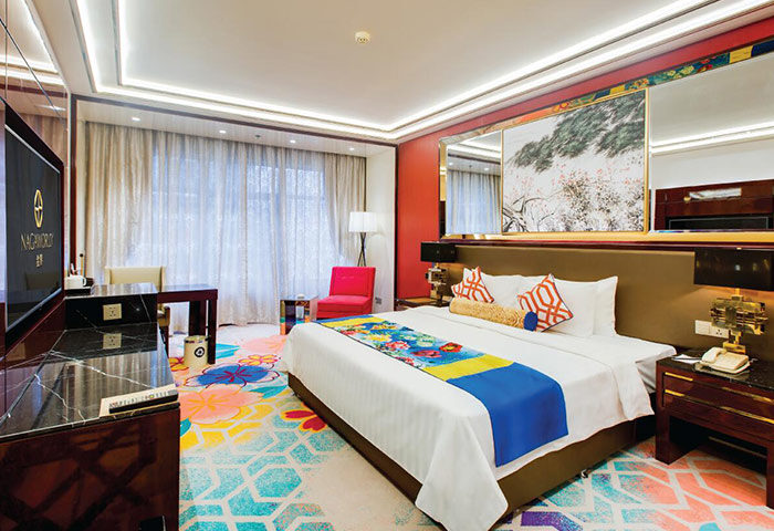 NagaWorld Hotel & Entertainment Complex room. Gay-friendly hotel with colorful carpet, bed runner, and decor. Luxury travel for gay men.