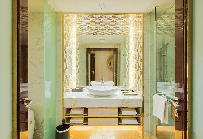 Bathroom at NagaWorld Hotel & Entertainment Complex, a gay-friendly hotel. Features modern sink, shower, & gold accents. Luxury travel.