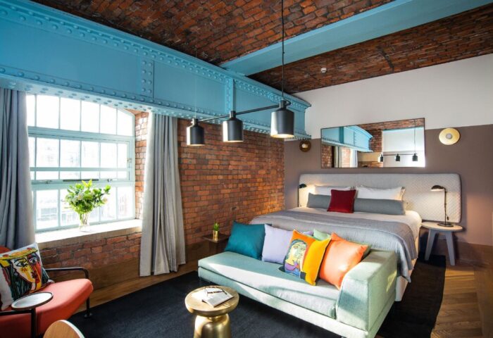 Native Manchester gay-friendly hotel room. Exposed brick, blue steel beams, and colorful pillows create a stylish, welcoming space.