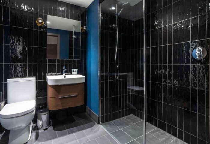 Modern bathroom at Native Manchester, a gay-friendly hotel. Features black tile, shower, sink, toilet. Ideal for gay travel.
