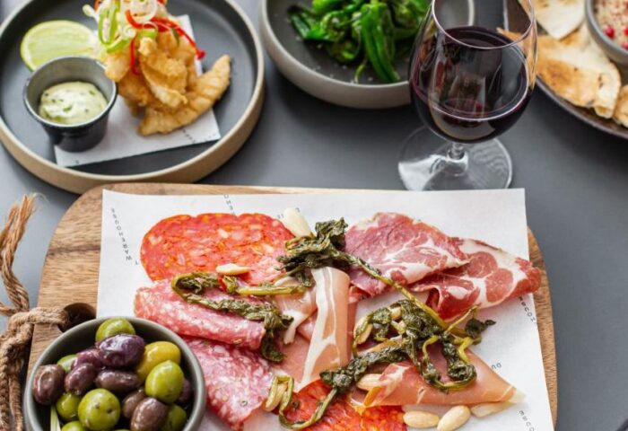 Gay-Friendly Hotel Native Manchester food. Charcuterie board with meats, olives, peppers, fish, and wine. Manchester gay travel.