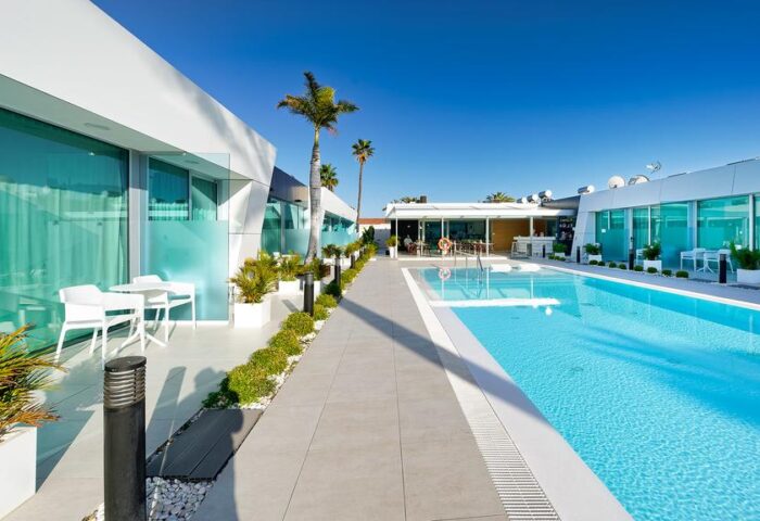 Hotel Nayra Adults Only pool view. Gay-friendly hotel with modern architecture, palm trees, clear blue pool, and lounge area. Perfect for gay travel.