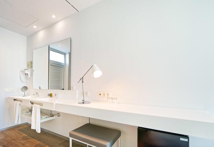 Hotel Nayra adults-only bathroom. Modern design with white walls, vanity, mirror, and stool. Gay-friendly hotel room interior, perfect for gay travel.