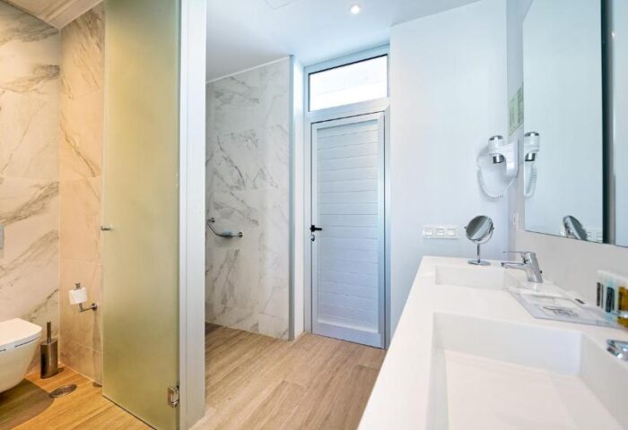 Hotel Nayra Adults Only bathroom. Gay-friendly hotel bathroom with toilet, shower, double sink, and amenities. Modern design.