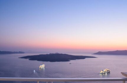 Sunset view from Nefeles Luxury Suites, a gay-friendly hotel. Wine glasses on table, sea view. Perfect for gay travel in Santorini.