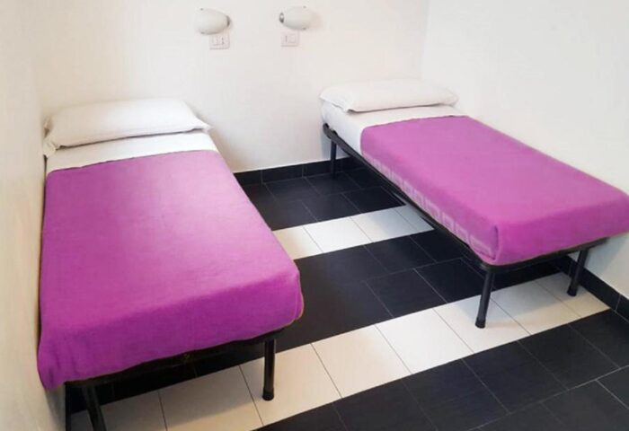 New Generation Hostel Milan Center: Gay-friendly hotel room with two single beds and purple blankets, black and white striped floor.