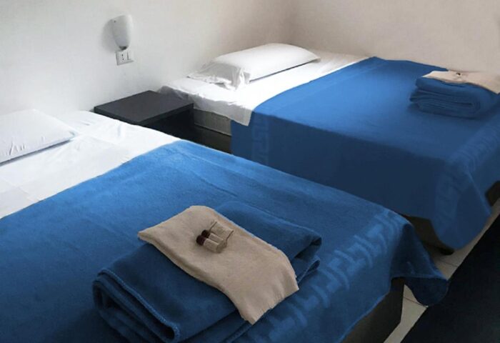New Generation Hostel Milan Center gay-friendly hotel room. Twin beds with blue blankets and white linens. Travel accommodation.