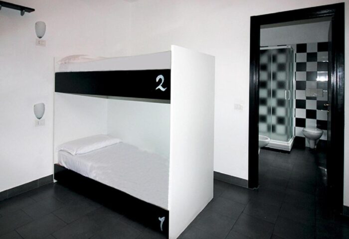 New Generation Hostel Milan Center gay-friendly room. Bunk beds and bathroom with black and white checkered tiles.