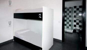 New Generation Hostel Milan Center gay-friendly room. Bunk beds and bathroom with black and white checkered tiles.