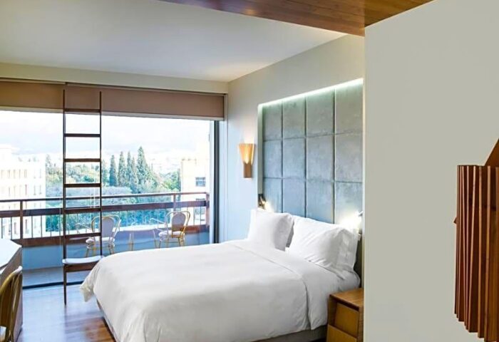 Gay-friendly New Hotel room with balcony. Modern design, white linens, and city view. Ideal for gay travelers seeking comfort and style.