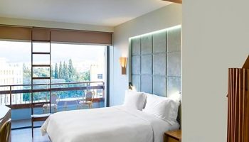Gay-friendly New Hotel room with balcony. Modern design, white linens, and city view. Ideal for gay travelers seeking comfort and style.