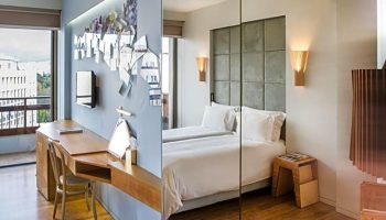 Gay-friendly New Hotel room featuring a desk, TV, and decor on one side, and a bed with a padded headboard and bedside table on the other.