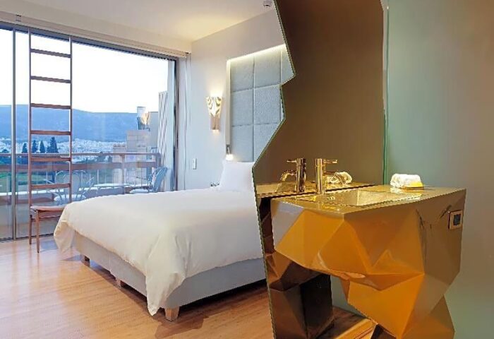 Gay-friendly New Hotel room with a balcony, bed, and a modern golden sink. A great option for gay men's travel.