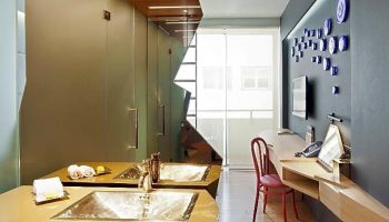 Gay-friendly New Hotel room: Modern bathroom with double sinks, desk, chair, and TV. Stylish design for gay men's travel.