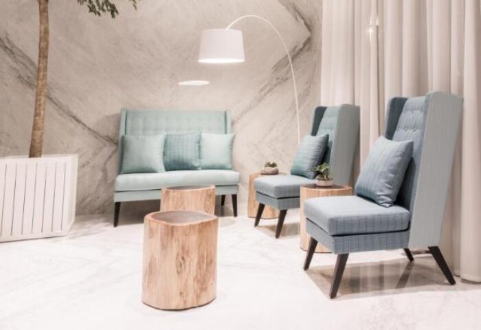 New Riverview Suites gay-friendly hotel: stylish lobby area with modern seating, light blue chairs, and wooden side tables. Interior design.