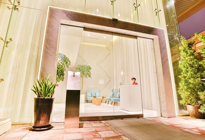 New Riverview Suites gay-friendly hotel entrance. Modern design with glass doors, plants, and a welcoming reception area. Stylish travel.