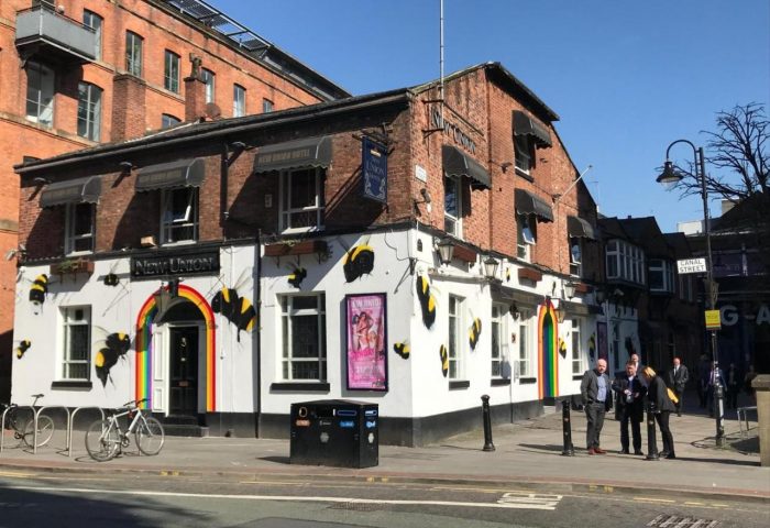 New Union Guesthouse, a gay-friendly hotel in Manchester. The building's exterior features rainbow decor and bee artwork, a symbol of the city.