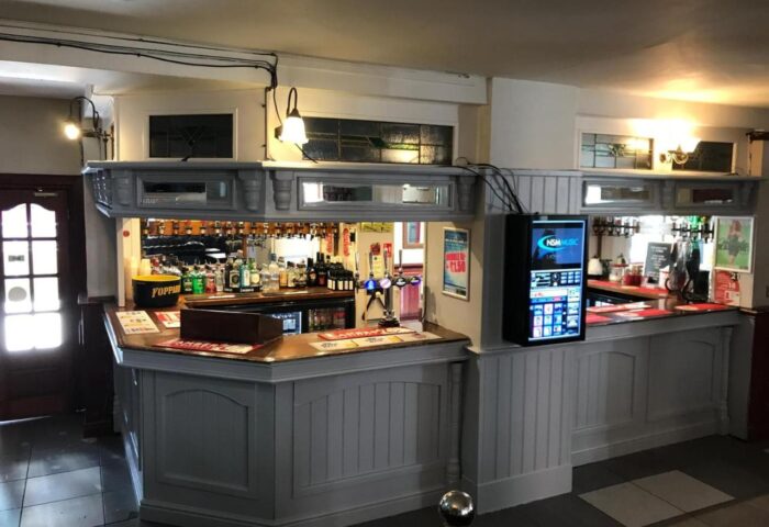 Bar area at New Union Guesthouse, gay-friendly hotel. Drinks, bottles, and a digital jukebox are visible. Interior of the bar at this hotel.