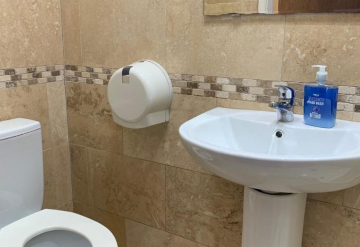 Bathroom at New Union Guesthouse, a gay-friendly hotel. Toilet, sink, mirror, and hand soap. Clean, tiled interior. Gay travel accommodation.
