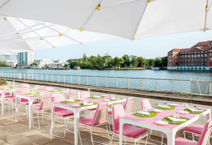 Nhow Berlin Hotel's gay-friendly outdoor dining area. Tables with pink chairs overlook the Spree River. A great spot for gay travelers.