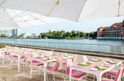 Nhow Berlin Hotel's gay-friendly outdoor dining area. Tables with pink chairs overlook the Spree River. A great spot for gay travelers.