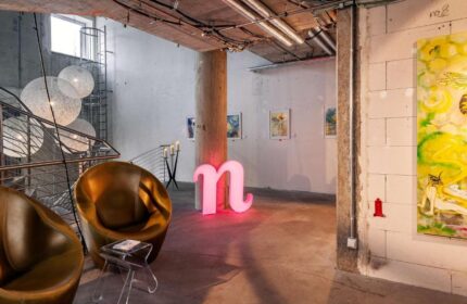 Nhow Berlin Hotel lobby. A gay-friendly hotel with a modern design, featuring lounge chairs, art, and a pink n logo. Unique hotel for gay travelers.