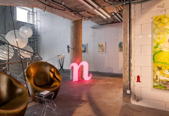 Nhow Berlin Hotel lobby. A gay-friendly hotel with a modern design, featuring lounge chairs, art, and a pink n logo. Unique hotel for gay travelers.